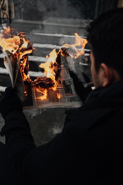 A compelling shot of a man holding a burning newspaper, capturing a dramatic moment.